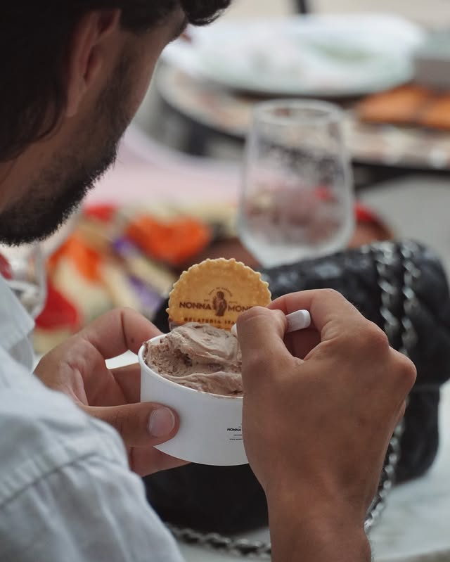 A guest lifting the branded wafer from a tub of chocolate gelato.