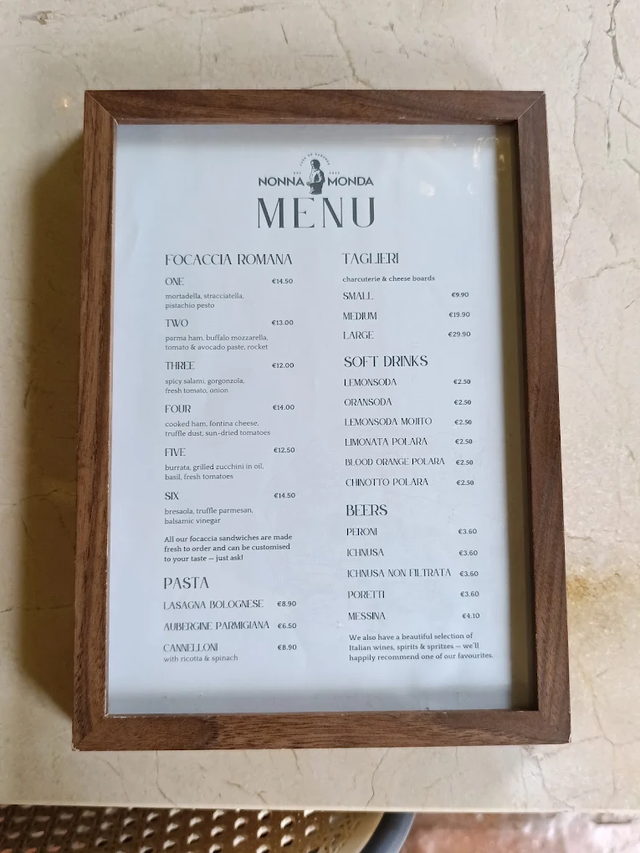 The printed Nonna Monda menu in a wooden frame on a marble table.