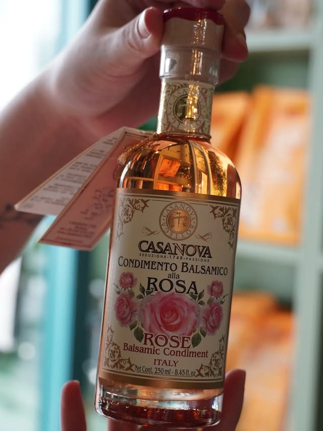 A bottle of Casanova rose balsamic condiment held up to the light.