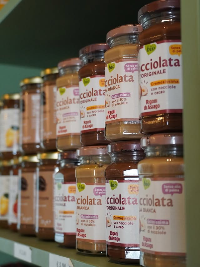 A row of Nocciolata hazelnut and cocoa spread jars along a shelf.