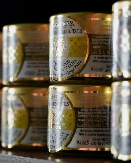 Stacked gold tins of extra virgin olive oil pearls.
