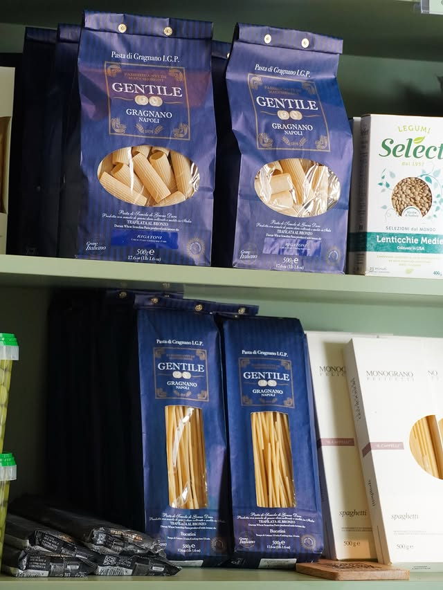 Blue paper packets of Gentile Pasta di Gragnano rigatoni and bucatini on the shelf.