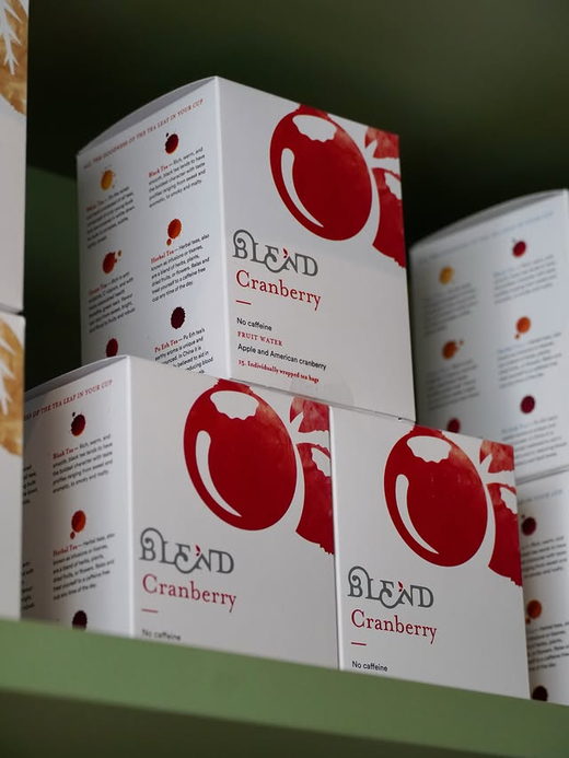 Boxes of Blend Cranberry fruit infusion stacked on a sage shelf.